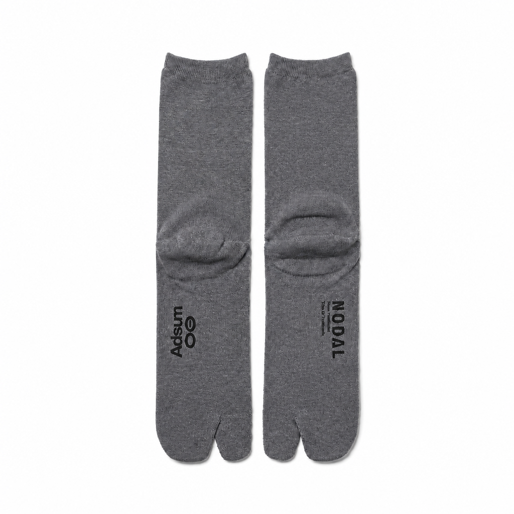 Adsum and NODAL co-branded Grey tabi socks on a color-matched white background